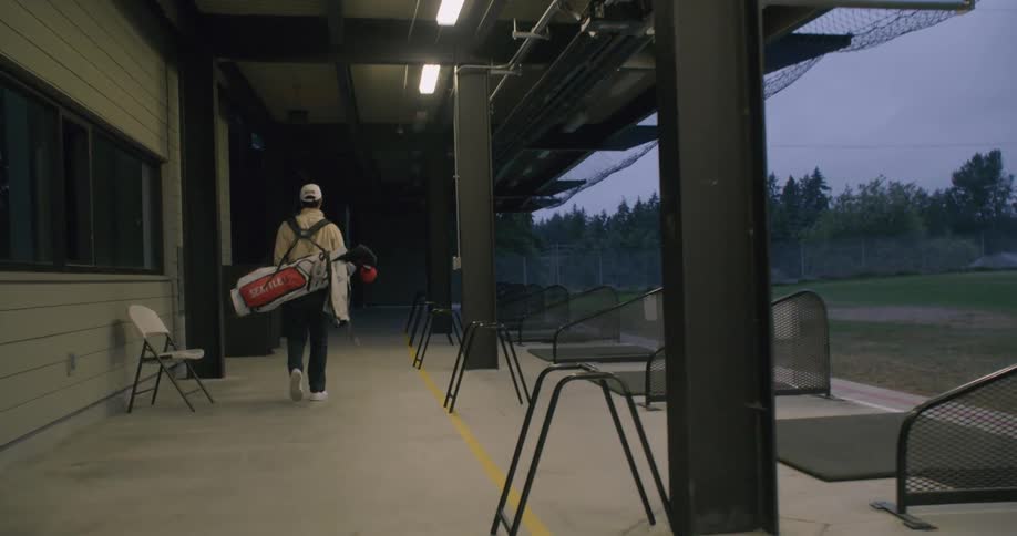 Person carrying a golf bag walks outside of a building