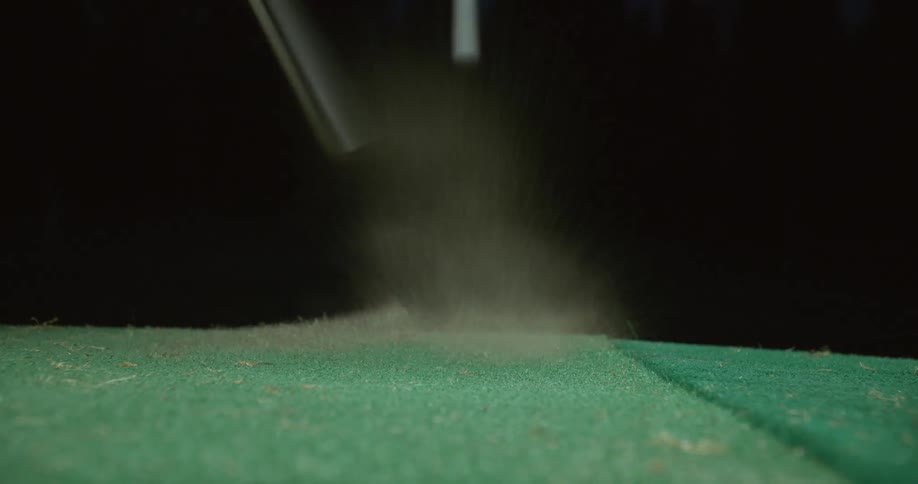 Golf club hits a ball on astro turf