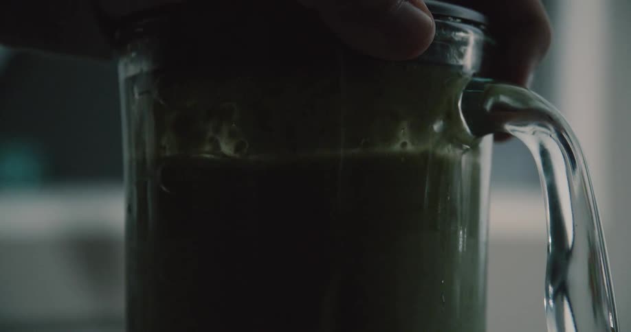 Person holds the top of a blender as it mixes liquid
