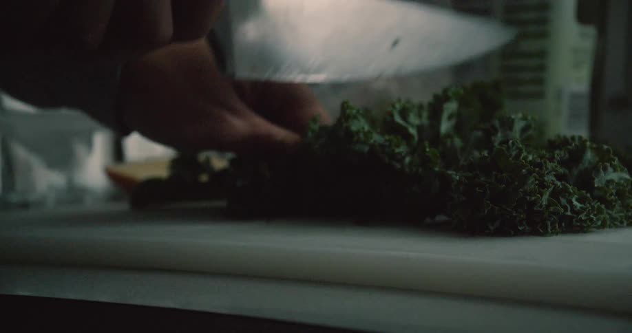 Knife chops into lettuce on a cutting board