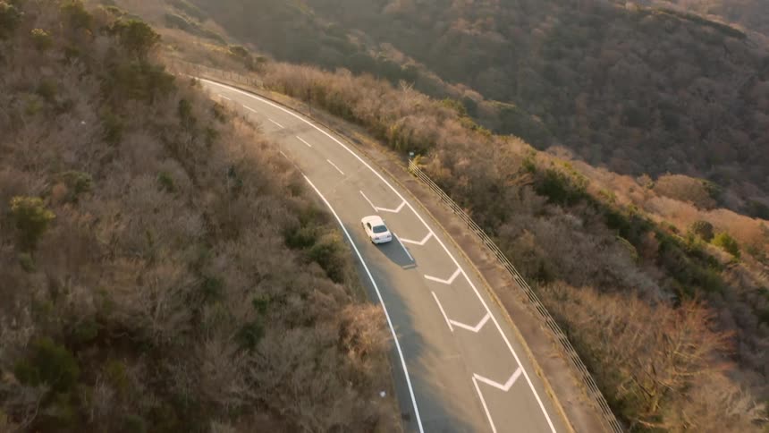Car drives down a winding country road on a sunny day