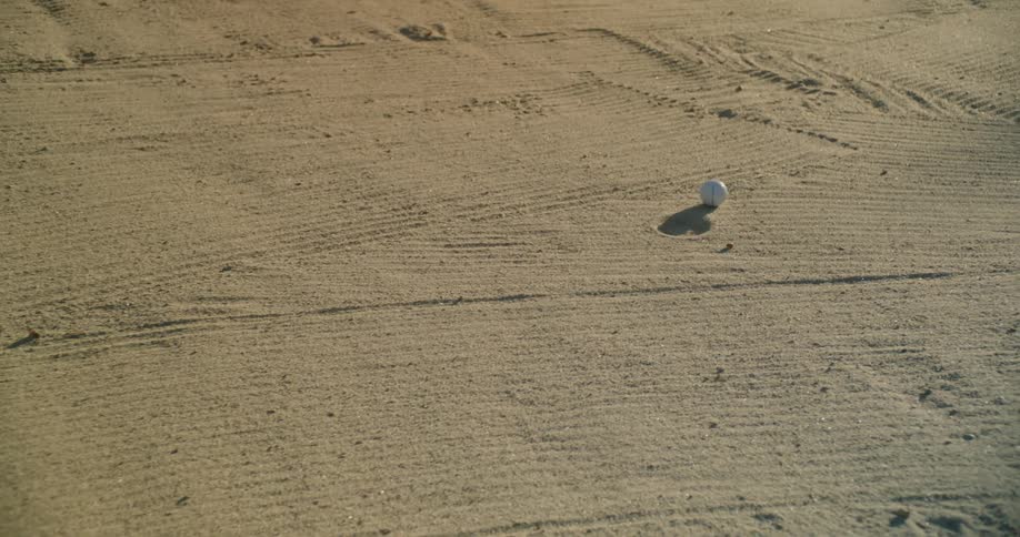 Golf ball lands on sand during the day