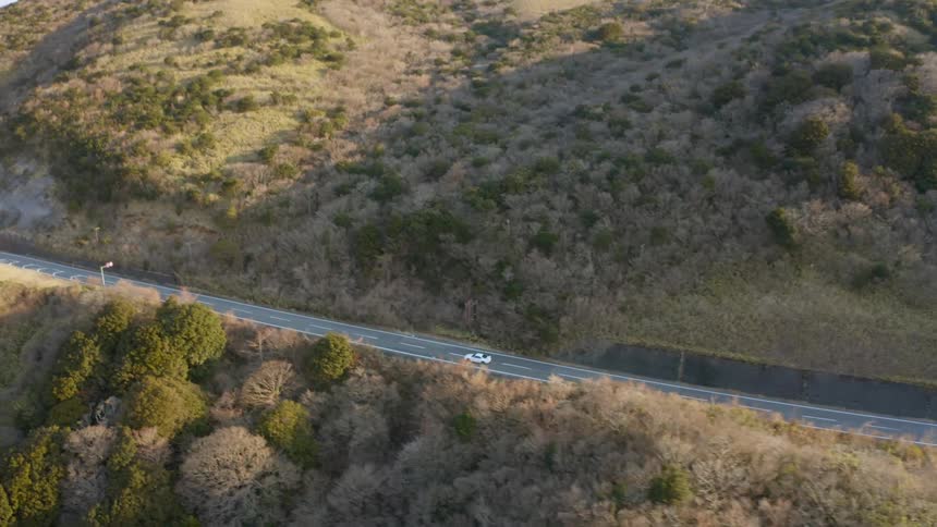 A car travels on a mountain road on a sunny day