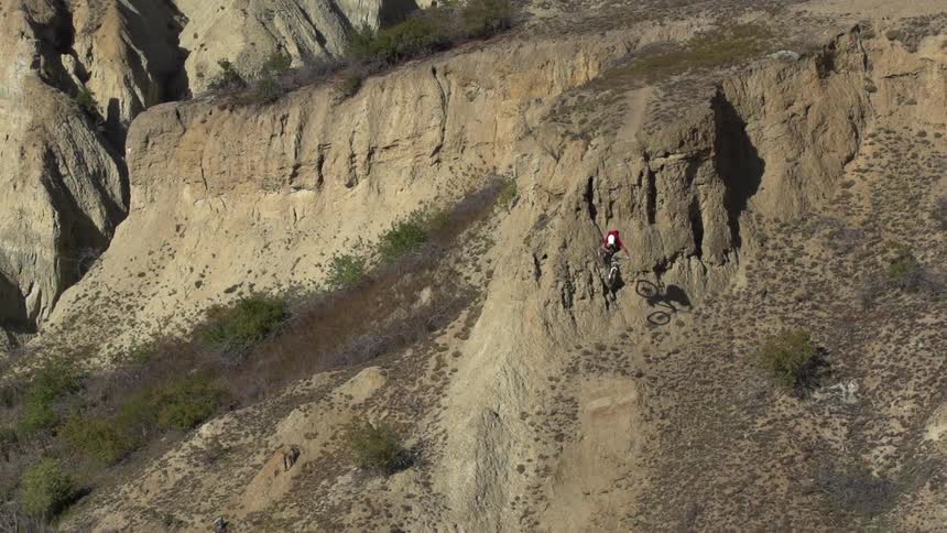 A bicyclist rides down a cliff in the wilderness