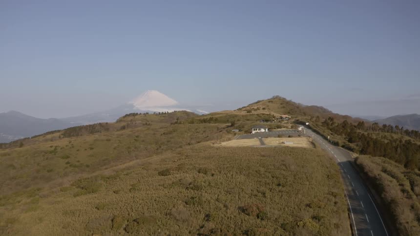 A car travels on a road on top of a hill on a sunny day