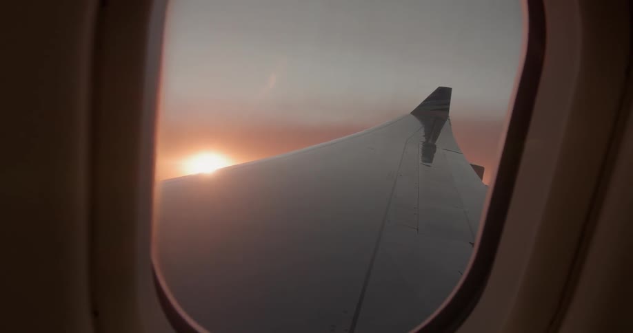 Sun sets behind an airplane wing