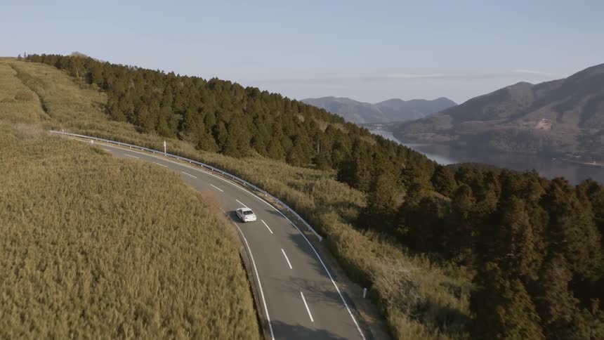 A white car travels down the highway under a blue sky