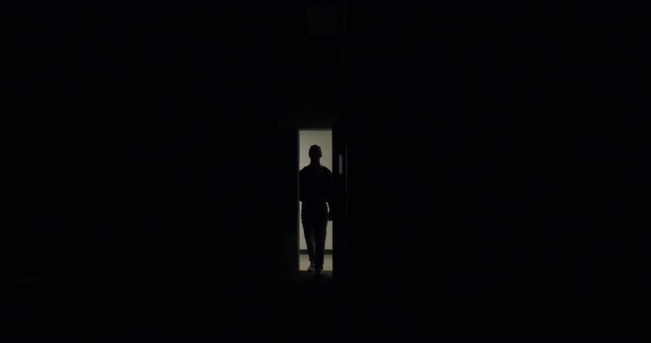A man walks through a door and turns on the lights