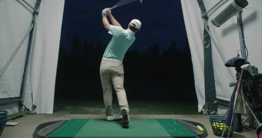 Man swings a golf club in a golf simulator