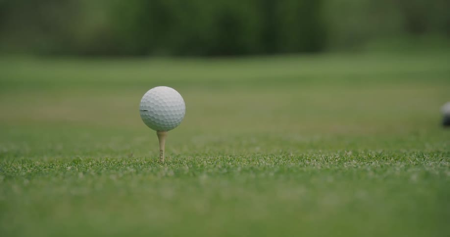Golf club hits a ball on a tee