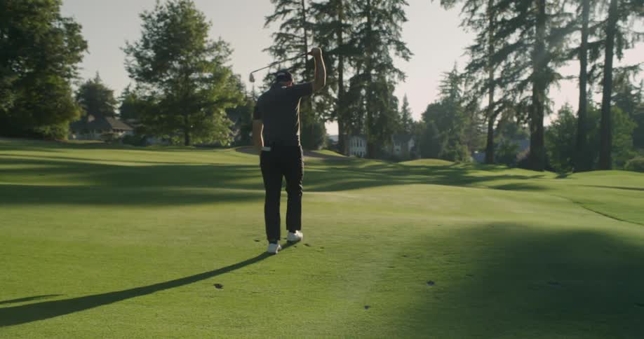 A golfer bangs his club against the grass as he walks away