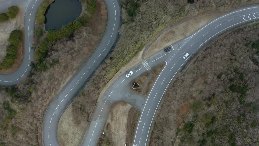 A vehicle is driving on a winding road in a natural landscape in daylight