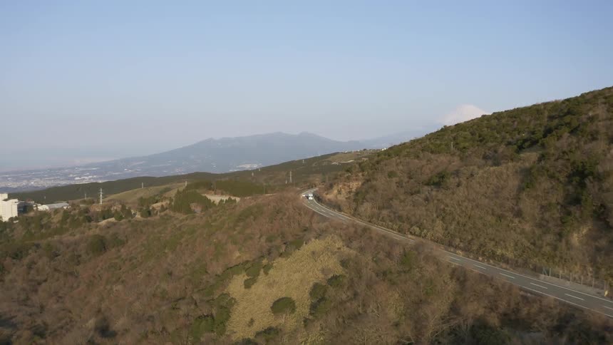 Cars and trucks travel on a road winding around a hill