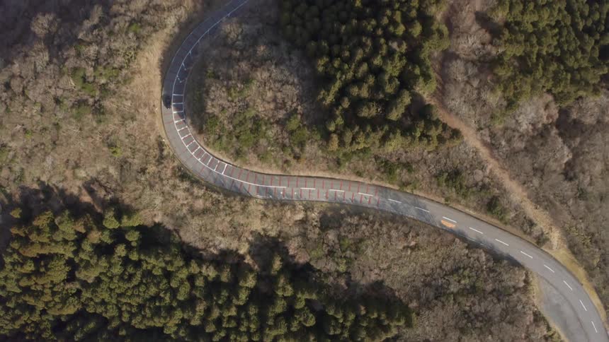 Car drives down a winding country road on a sunny day