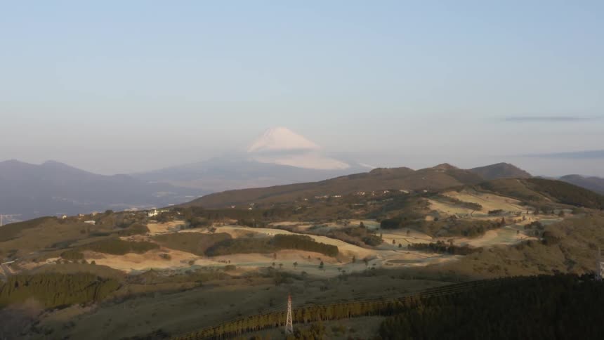 The green hills are covered with fog in the distance