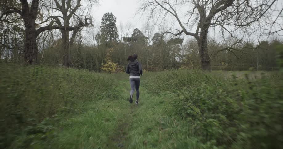 The woman is jogging over the trail