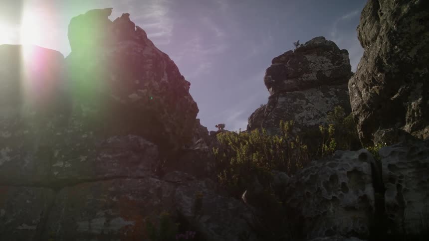 Man jumps over the rocks under a sunny blue sky