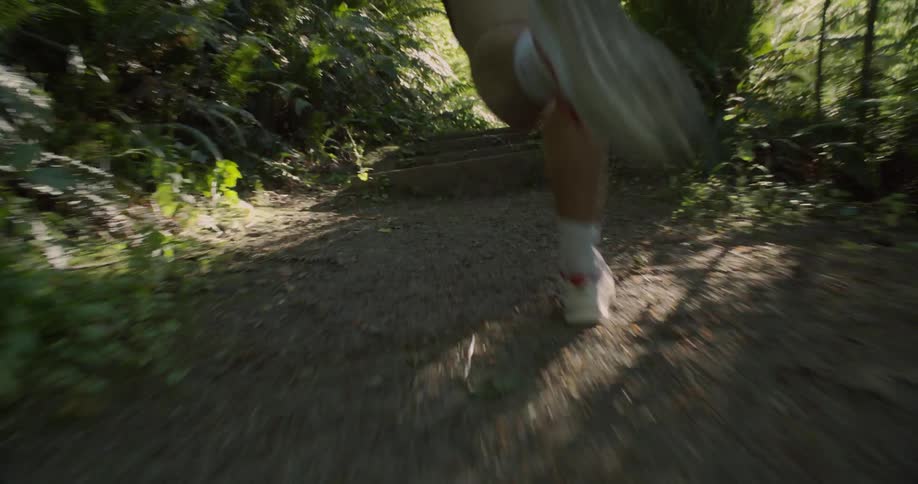 A man is jogging on a dirt trail in a natural setting during the day