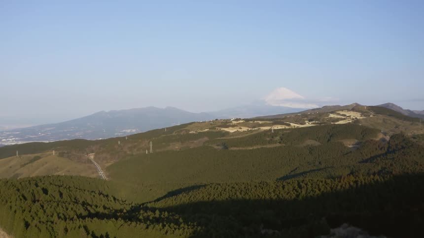 Sun shines over grassy hilly landscape