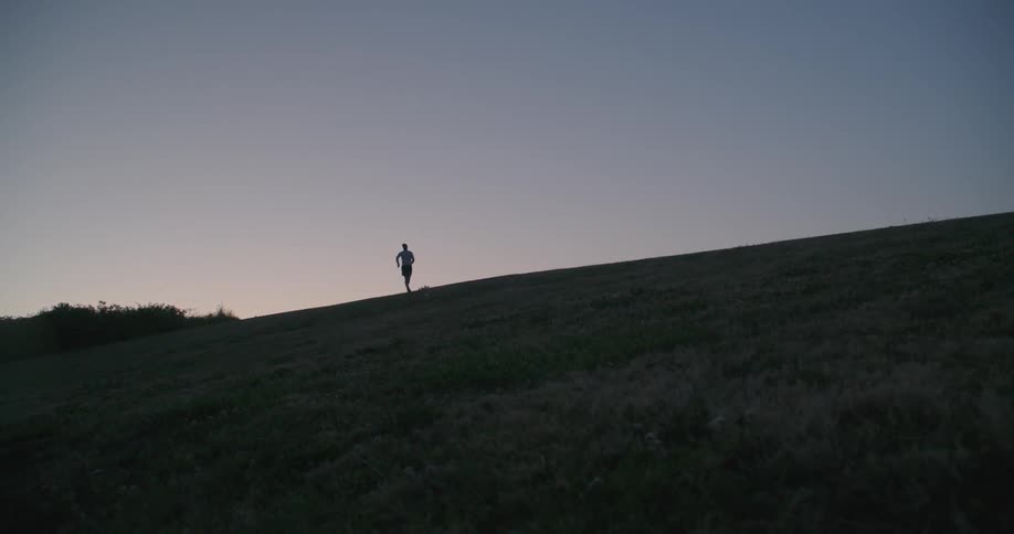 Person running up a hill at sunset