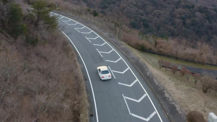 White car drives down a winding country road
