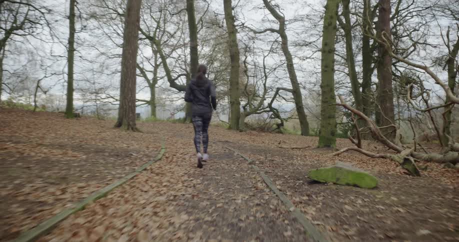 Woman jogging on path in wooded area in the fall