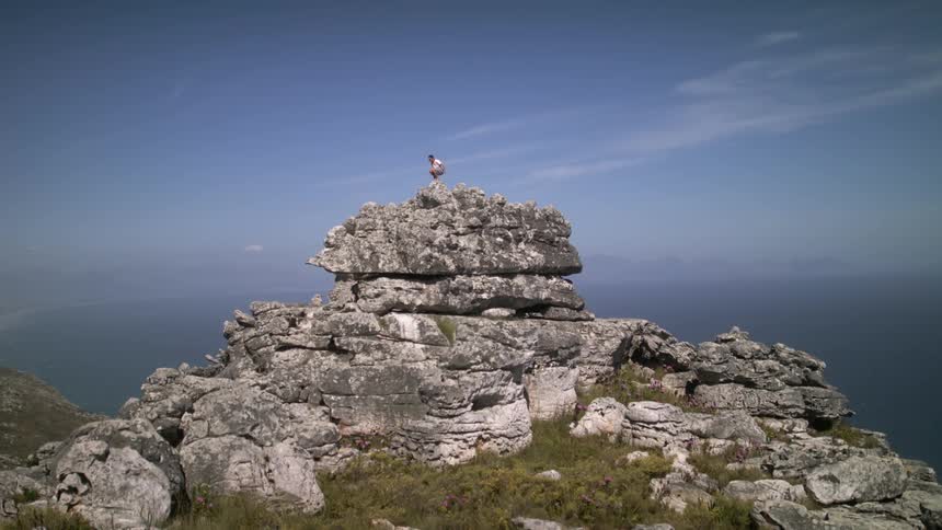 A person jumps down from the top of the large rocks