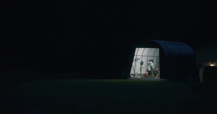 Person practices golf in a small room at night