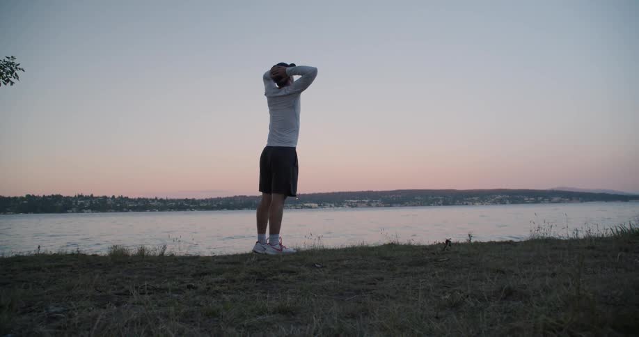 Man leans over and stands up near a body of water