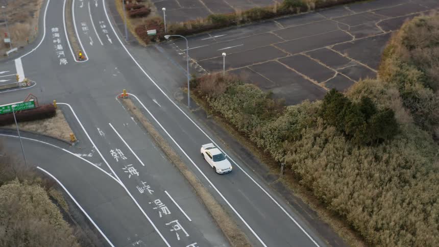 The white car is parked on the road below