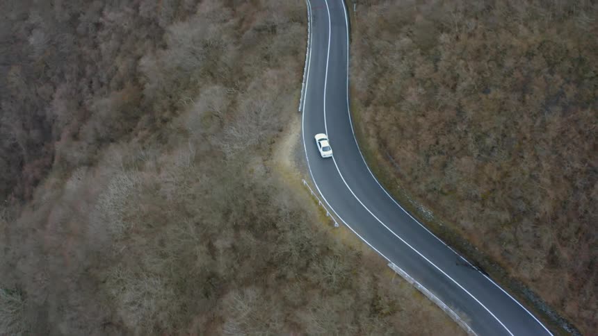 Car drives down a winding country road