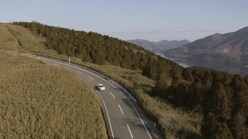 Car drives down a winding country road on a sunny day