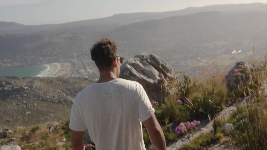 Man walks on hilly mountains on a sunny day