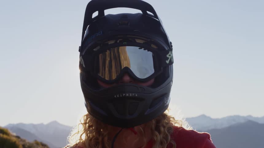 A person in a helmet standing by a bike