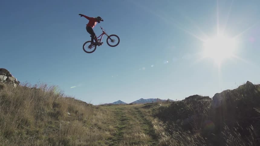 A mountain biker is jumping over trail