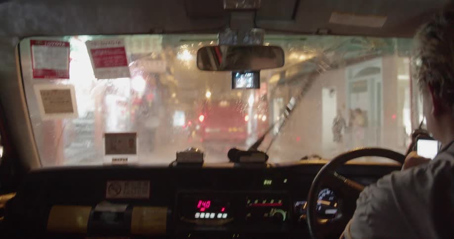 Car drives on a busy city street on a rainy night
