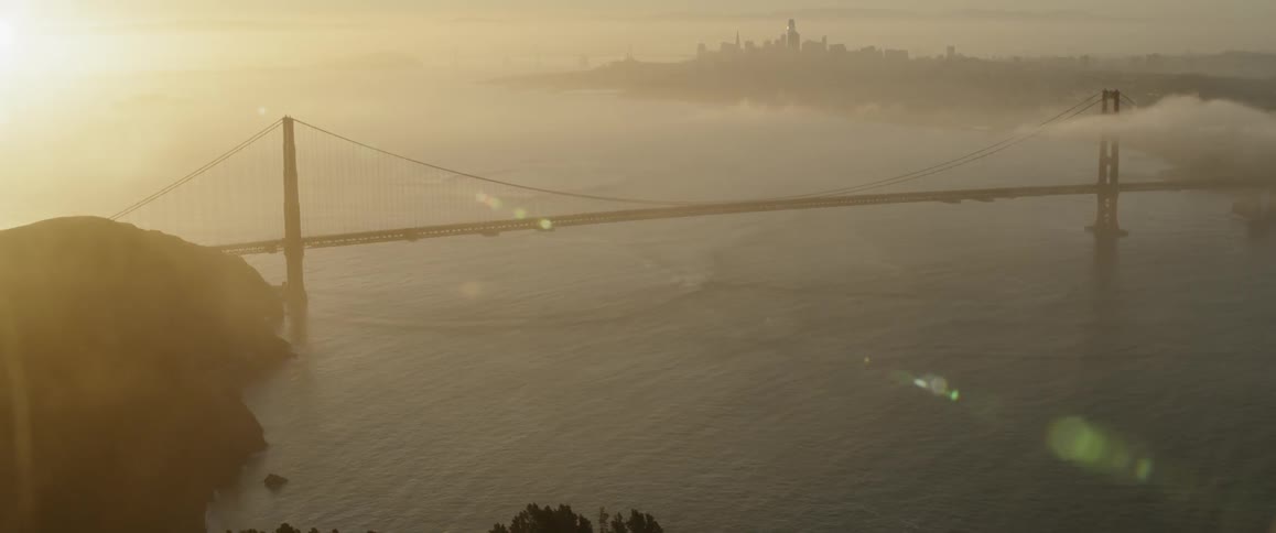 The vehicles travel over the bridge at sunrise
