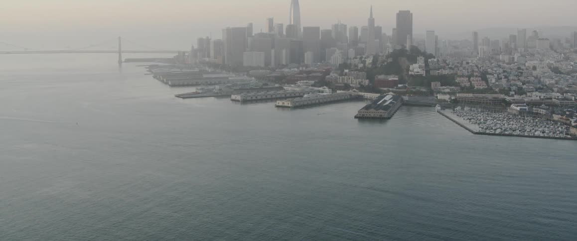 The calm water leads to the city covered with fog