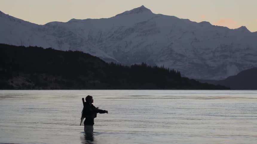 Man is fly fishing knee high in water