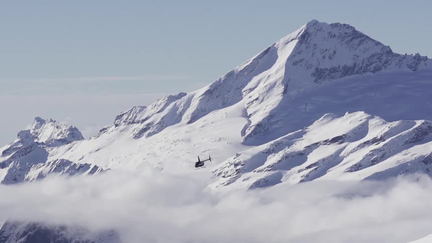 A helicopter flying past a mountain