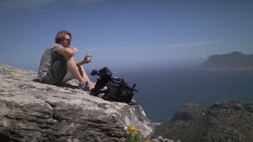 A man eats at the edge of a cliff