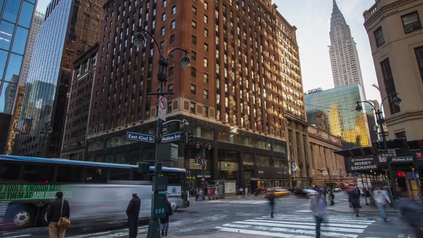 Pedestrians cross a city street and traffic moves through the intersection