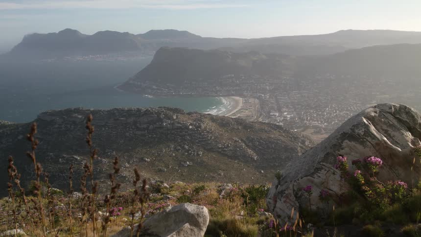 Haze is lingering in the air over a community on a rugged coastline during the day