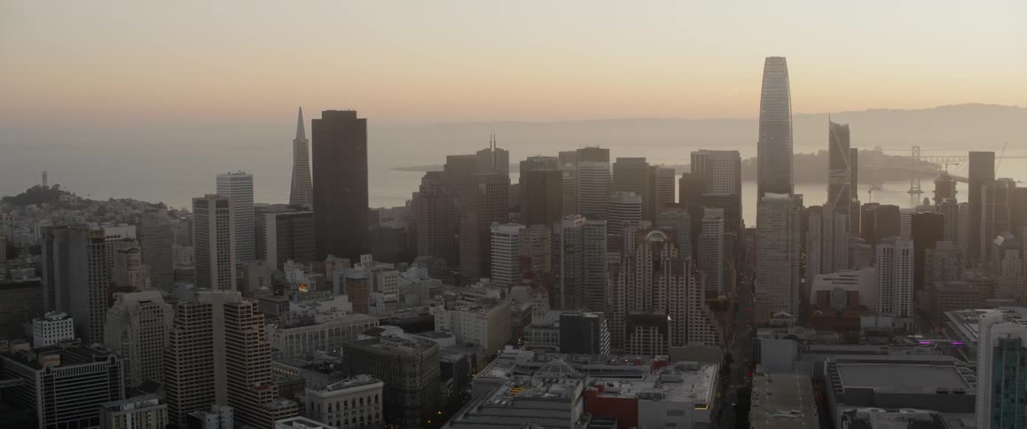 The sun is setting near the city with large buildings