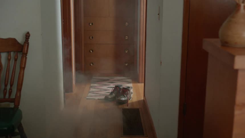 White smoke billows out of a room at the end of a hallway