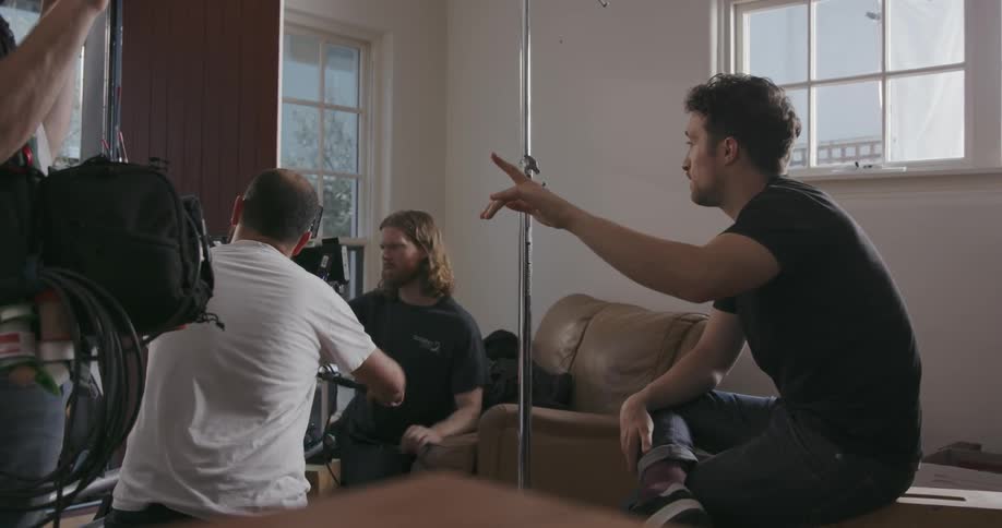Three men film a video with large camera equipment in a house