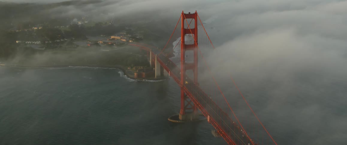 Clouds roll over a large bridge near a city
