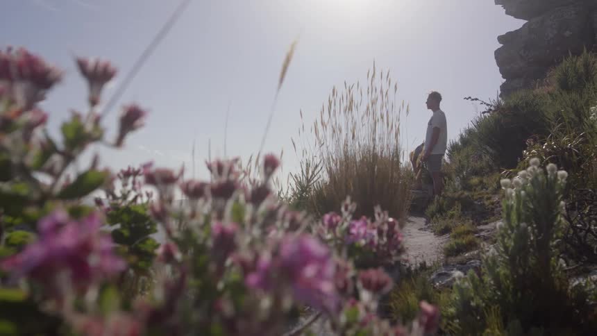 Man sits outside in a garden with sun shining down