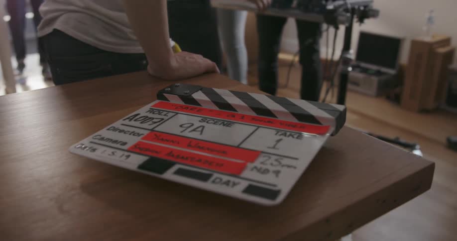 A slap stick rests on a film site as a crew works