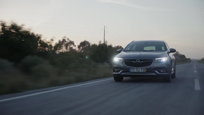Vehicle drives down a country road at sunset